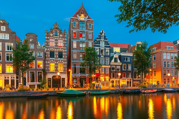 Vista della città di notte del canale Herengracht di Amsterdam, delle case olandesi tipiche e delle barche, Olanda, Paesi Bassi.