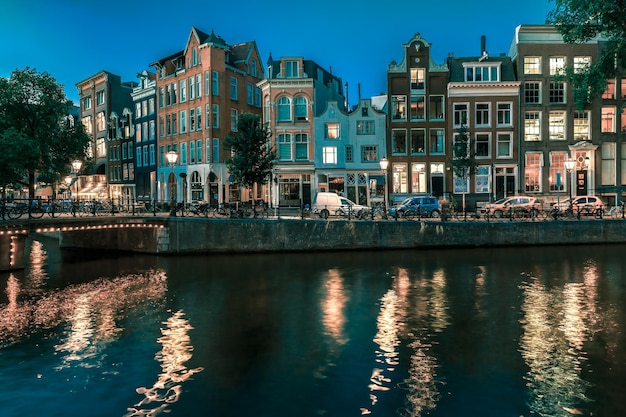 Vista della città di notte delle case olandesi tipiche del canale di amsterdam e del ponte olanda Paesi Bassi che tonificano in coo...