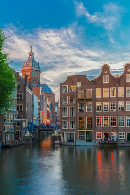 Vista della città di sera del canale, del ponte e delle case tipiche di Amsterdam, Olanda, Paesi Bassi. Esposizione prolungata.