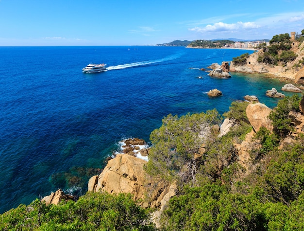 Vista della costa rocciosa del mare d'estate con il castello di Sant Joan e la barca (città di Lloret de Mar, Catalogna, Spagna).