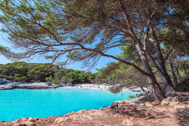 Vista della famosa spiaggia di Cala Turqueta. (Focus sul primo piano, persone sulla spiaggia sfocate). Minorca, Isole Baleari, Spagna