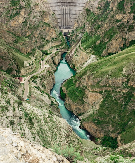 Vista della parte inferiore della diga ad arco con uno sfioratore e un fiume di montagna in un canyon