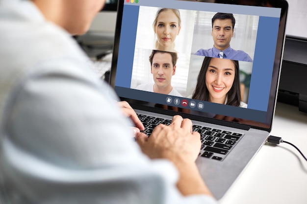 Vista della parte posteriore dell'uomo utilizzando la videoconferenza portatile e lavorando con il collega