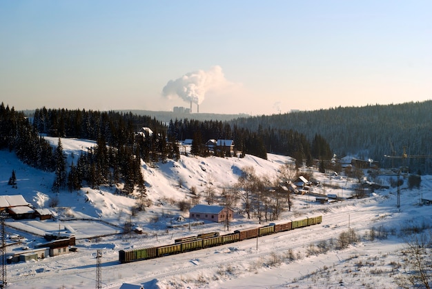 Vista della piccola stazione ferroviaria nella valle invernale con vagoni merci in piedi