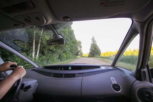 Vista della strada di campagna forestale attraverso il vetro dell'auto durante il viaggio