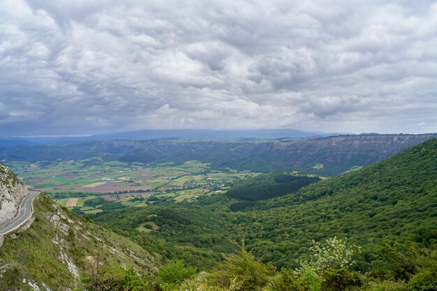Vista della valle dall'alto sul campo verde di una giornata nuvolosa con sentiero di montagna