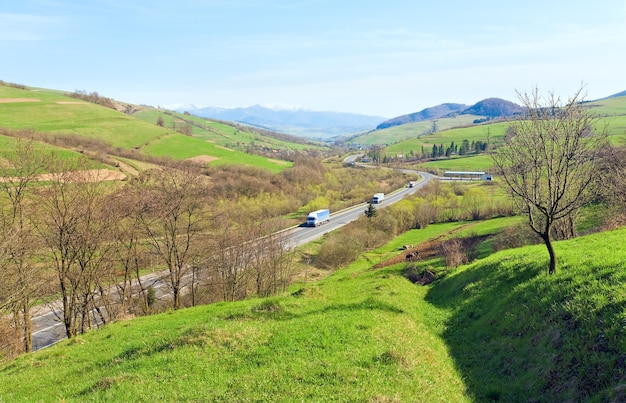 Vista della valle del paese di montagna primaverile con campi agricoli e strada