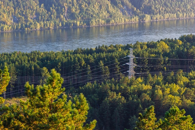 Vista delle linee elettriche che passano attraverso le colline della foresta sullo sfondo del fiume