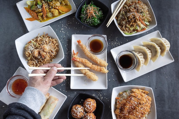 Vista delle mani dell'uomo che mangiano con le bacchette in un ristorante orientale