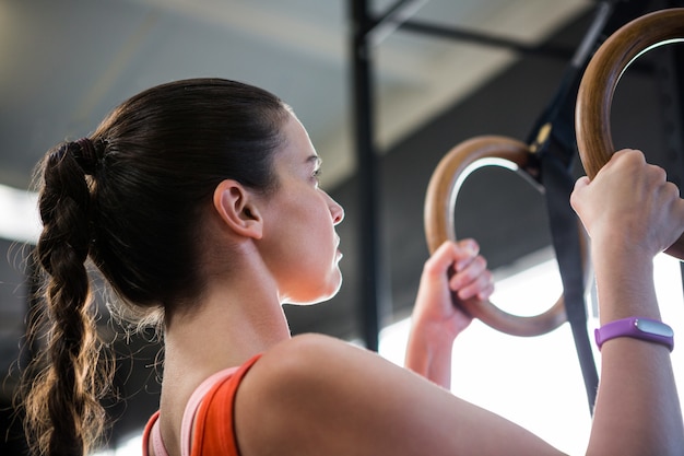 Vista di angolo basso dell'atleta femminile che tiene gli anelli relativi alla ginnastica