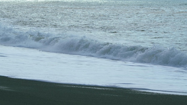 Vista di grandi onde bellissime spruzzando acqua di mare tempestosa sullo sfondo ondate di mare sulla spiaggia con nero