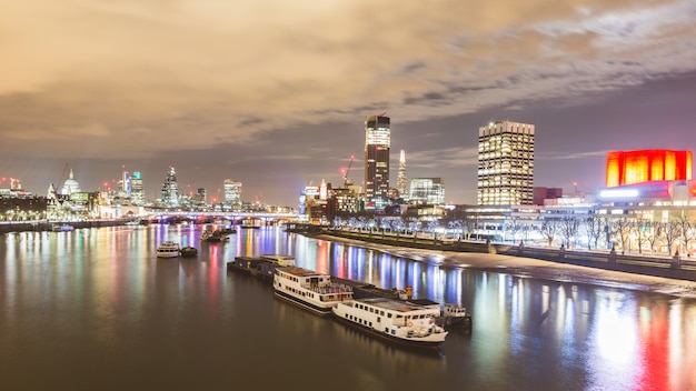 Vista di Londra di notte con barche e grattacieli