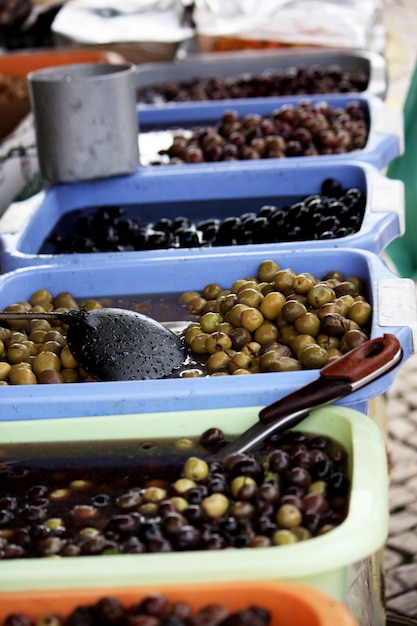 Vista di molti secchi pieni di molti tipi di olive, tra cui verdi, neri e marroni su un mercato.