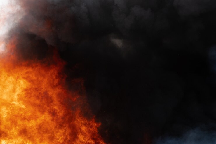 Vista di pericolose fiamme rosse di fuoco enorme e nuvole di movimento del cielo coperto di fumo nero. Sfocatura, sfocatura del movimento da fuoco forte e alta temperatura dalle fiamme. Dispersione atmosferica e di fumo.