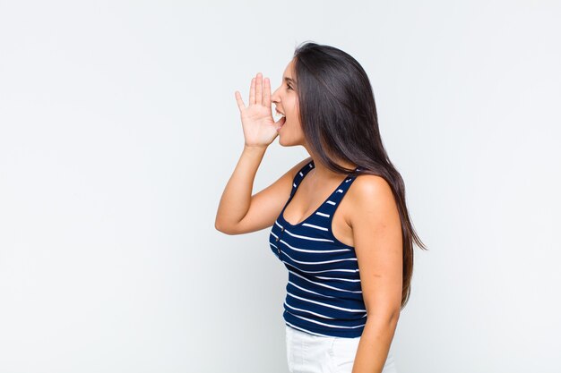 Vista di profilo della giovane donna, che sembra felice ed eccitata, gridando e chiamando per copiare lo spazio sul lato