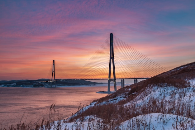 Vista di tramonto di inverno con neve fresca e ponte strallato lungo a Vladivostok, Russia