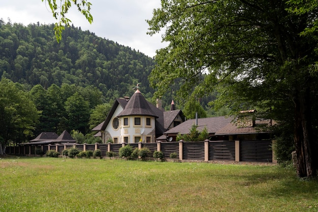 Vista di un cottage nel villaggio di Guzeripl sullo sfondo delle montagne del Caucaso in una soleggiata giornata estiva con nuvole Guzeripl Repubblica di Adygea Russia