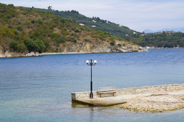 Vista di una lanterna e di una panchina in riva al mare Corfù in Grecia