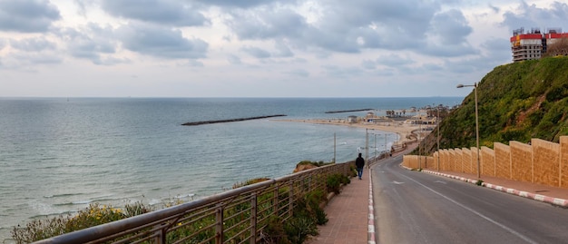 Vista di una strada panoramica che conduce a una spiaggia sabbiosa durante una giornata nuvolosa