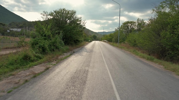 Vista di una strada rurale da un'auto in movimento con le montagne in una giornata estiva