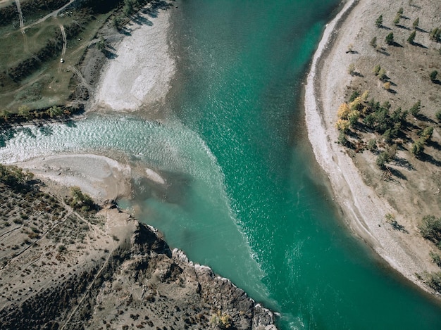 Vista dron su un lungo fiume turchese chiaro che si estende lungo le rive sabbiose, dividendosi in due direzioni alla fine del fiume
