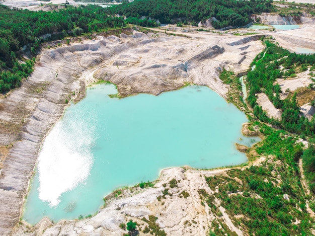 Vista drone su una cava di caolino allagata con acqua turchese e riva bianca