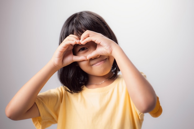 Vista e occhi sani Ritratto di un bambino asiatico sorridente con le mani a forma di cuore sugli occhi