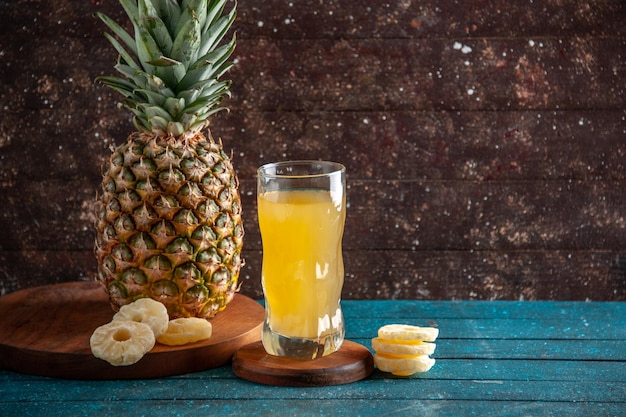 vista frontale ananas fresco fette di ananas secco succo in vetro su tavole di legno