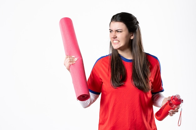 Vista frontale arrabbiato giovane femmina in abiti sportivi con materassino yoga