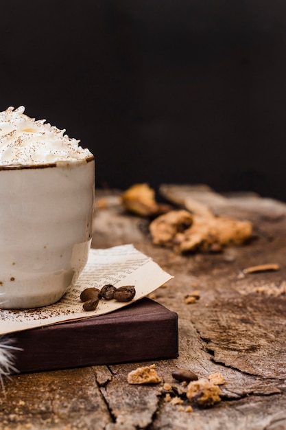 Vista frontale caffè con latte e panna montata con biscotto