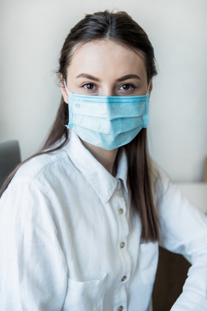 Vista frontale da vicino di una femmina nel professionista sanitario occhiali indossando una maschera chirurgica in un ospedale. Operatori sanitari nella pandemia di Coronavirus Covid19
