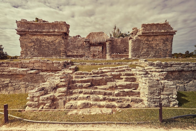 Vista frontale dei resti di un piccolo tempio Maya nel complesso di Tulum in Messico scattata al tramonto.