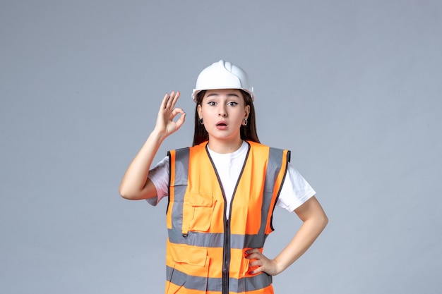 Vista frontale del costruttore femminile in uniforme sul muro bianco