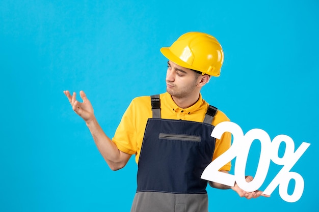 Vista frontale del giovane operaio maschio in uniforme con la scrittura sul pavimento blu