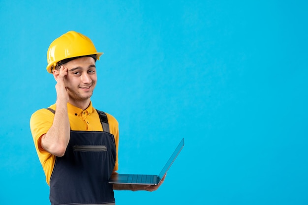 Vista frontale del lavoratore maschio in uniforme con il computer portatile sull'azzurro