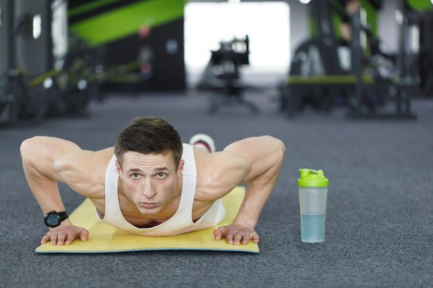 Vista frontale del ritratto dell'uomo del giovane atleta che fa esercizio di push up in palestra