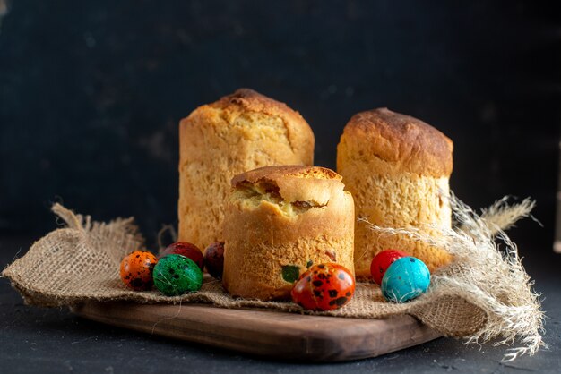 vista frontale deliziosa torta per pasqua con uova colorate sul tagliere sfondo scuro ornato pasqua colorato colore etnico vacanza