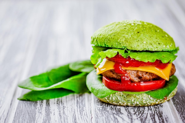 Vista frontale dell'hamburger verde fatto in casa con carne di manzo in marmo con verdure verdi sul tavolo di legno