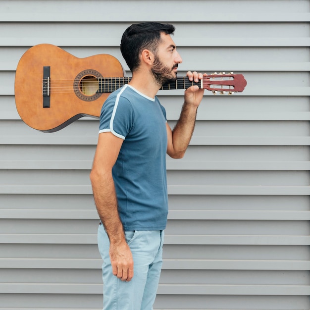 Vista frontale dell'uomo che tiene una chitarra sulla spalla