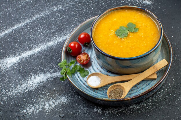 Vista frontale della deliziosa zuppa di lenticchie rosse in una ciotola servita con pomodori verdi pepe sale sul vassoio blu sul lato sinistro su sfondo bianco nero con spazio libero