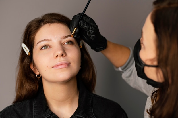 Vista frontale della donna che ottiene un trattamento per le sopracciglia da uno specialista femminile