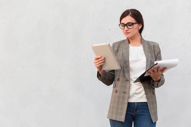 Vista frontale della donna di affari all'aperto con tablet e blocco note