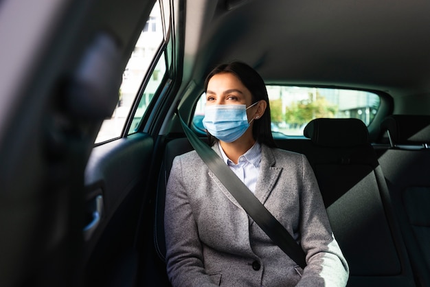 Vista frontale della donna di affari con mascherina medica in macchina