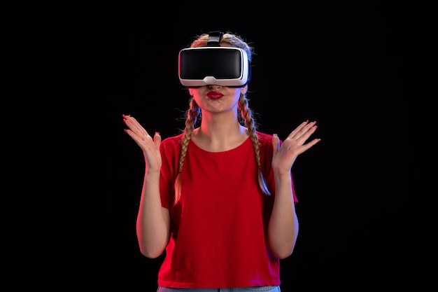 Vista frontale della giovane donna che gioca alla realtà virtuale sul muro scuro