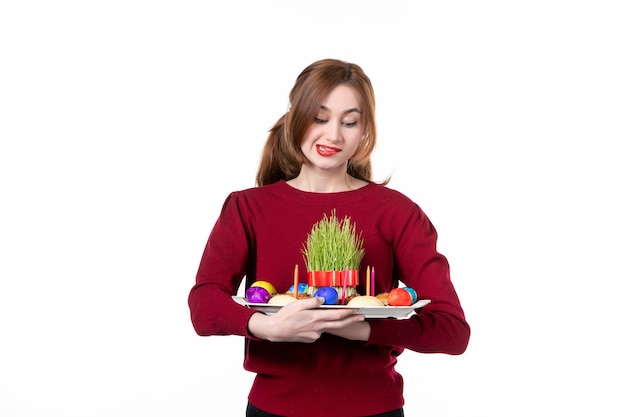 Vista frontale della giovane femmina holding honca con semeni e novruz dolci su sfondo bianco colori etnia performer concetto di vacanza etnica foto di primavera