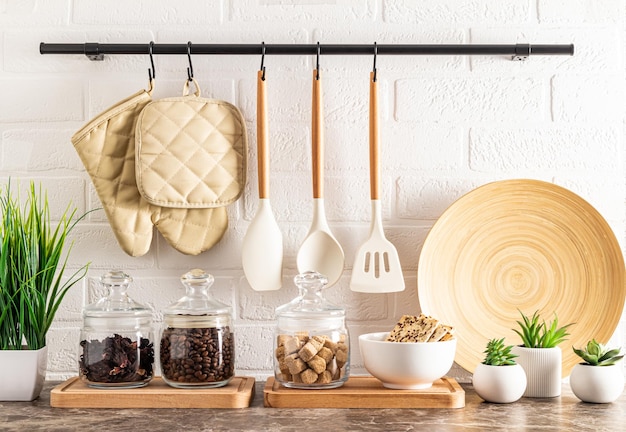 Vista frontale della parte del controsoffitto della cucina con un set di barattoli di vetro per conservare una ciotola con biscotti e piante d'appartamento in vaso muro di mattoni con ringhiera