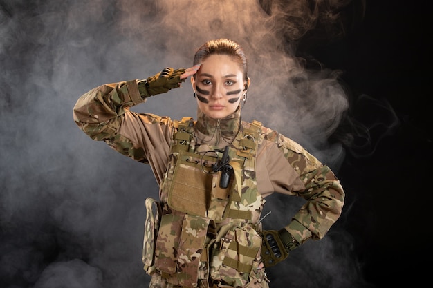 Vista frontale della soldatessa in mimetica sul muro scuro