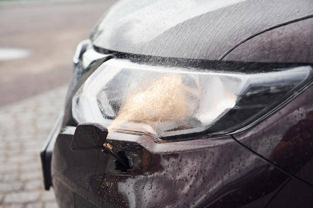 Vista frontale delle particelle di un'automobile moderna nera con i fari accesi