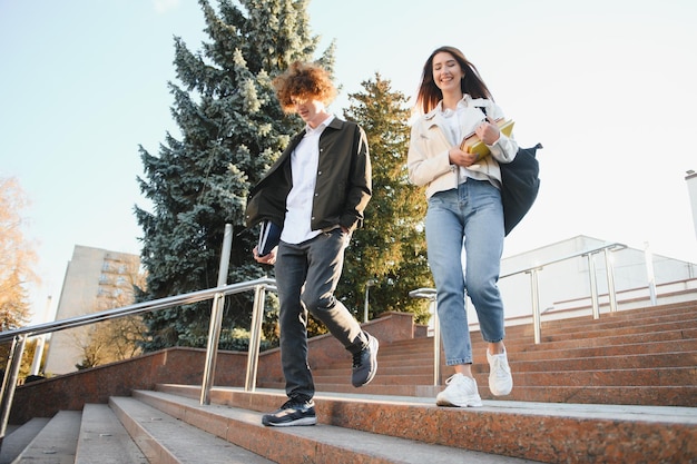 Vista frontale di due studenti che camminano e parlano in un campus universitario