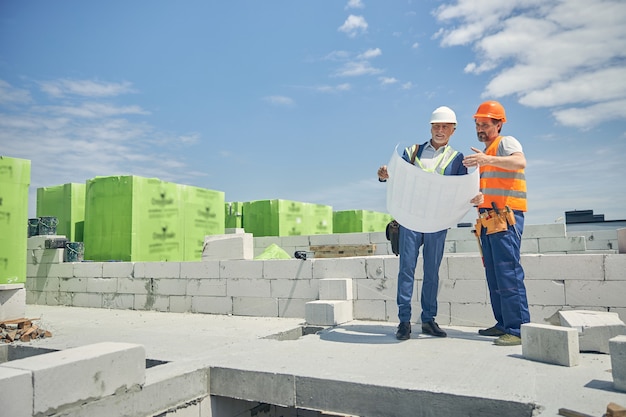 Vista frontale di un ingegnere civile e di un supervisore sorridente in piedi in un cantiere edile